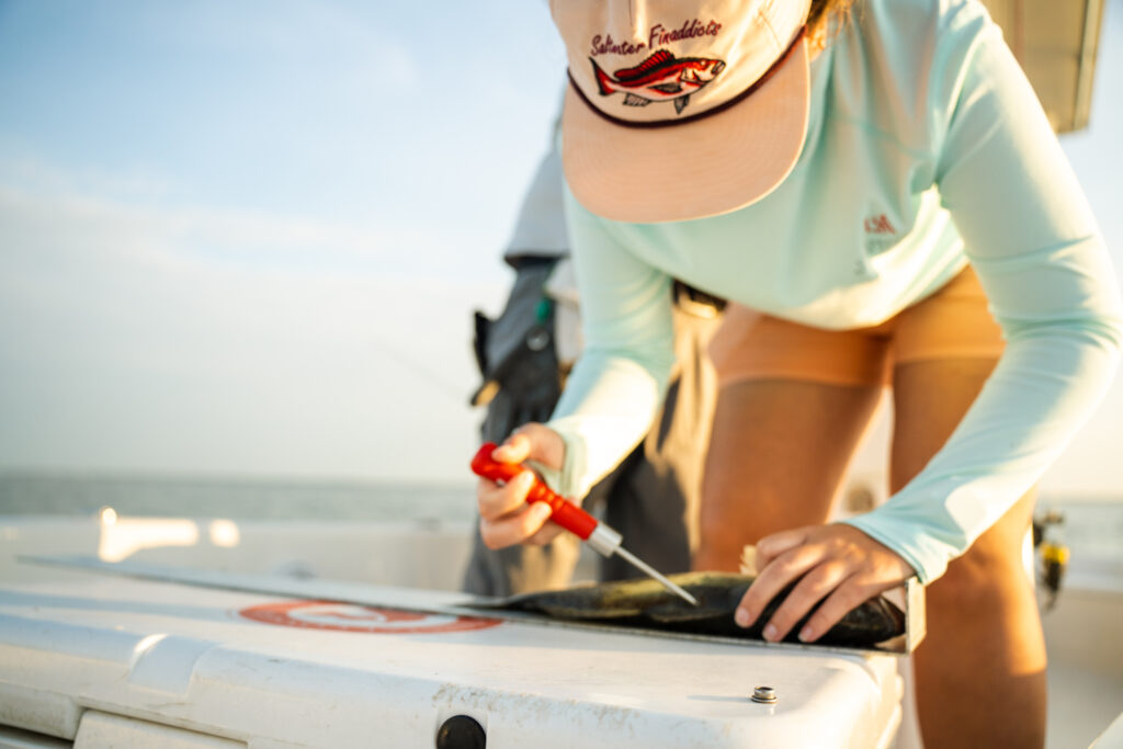 A female angler using the Toit Tagging tool to tag a fish